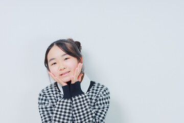 	頬に手のひらを当てた笑顔の小学生女子