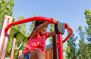 Little girl having fun playing in the playground in a park.