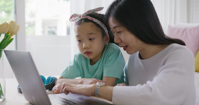 Cute asia people alpha small Gen Z kid fun talk play learn on smart tablet app game with mum at home sofa. Enjoy Child care little girl and mom happy smile relax teach study upskill idea online class.