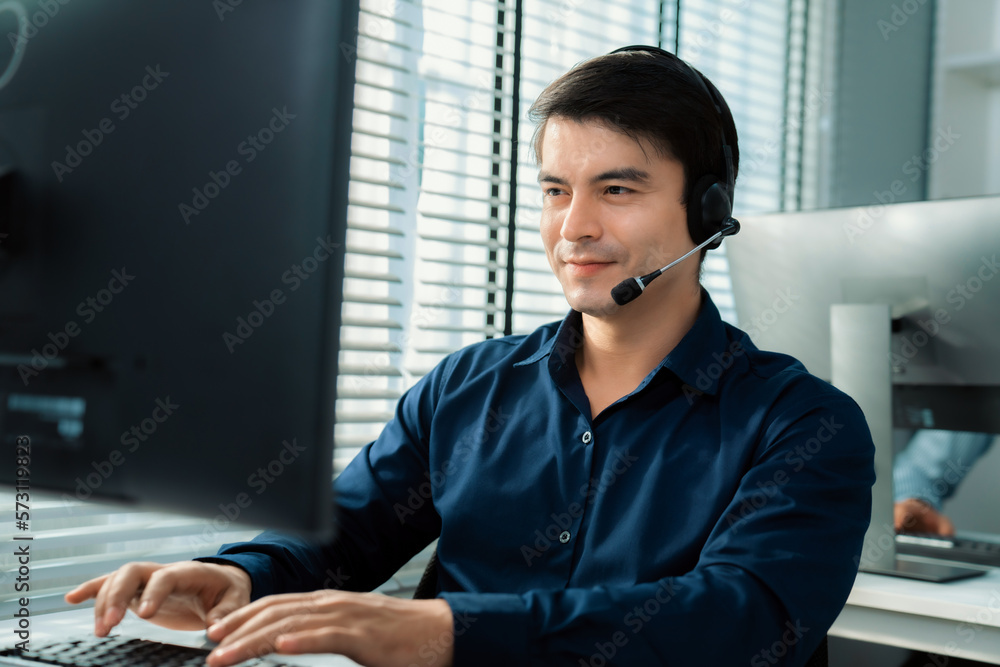 Aufkleber young competent asian male call center agent working at his computer while simultaneously speaking w