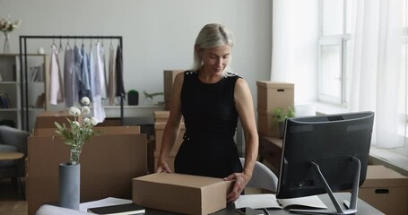 Mature woman packs items in box, ready for move-out to new house. Entrepreneurship, move day, bank loan, client of reliable transportation company for sending parcel to customer or relocation, small