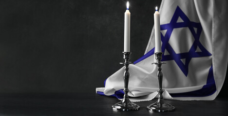 Fototapeta na wymiar Burning candles and flag of Israel on dark background with space for text