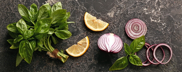 Fresh aromatic basil with onion and lemon slices on dark background