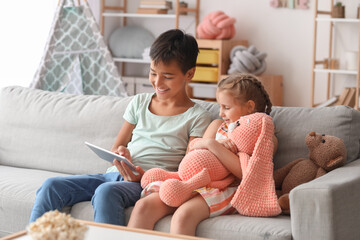 Fototapeta premium Little boy and girl watching cartoons on tablet computer at home