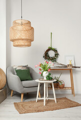 Vase with tulips and Easter rabbits on table in interior of living room
