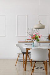 Interior of kitchen decorated for Easter celebration with tulips in vase on dining table