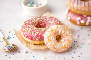 Naklejka na ściany i meble Parchments with different delicious donuts and bowls of sprinkles on white table