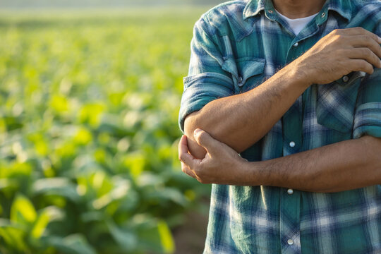 Injuries or Illnesses, that can happen to farmers while working. Man is using his hand to cover over elbow because of hurt,  pain or feeling ill.