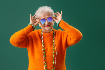 Senior woman with bright accessories on green background