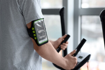 Man with mobile phone training in gym, closeup