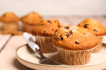 Plate of tasty muffins on light wooden table, closeup