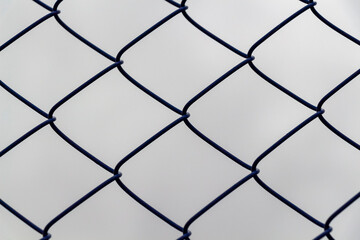 Fototapeta premium Chain-link fence against a gloomy gray sky.
