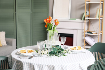 Dining table with setting for International Women's Day celebration and flowers in living room