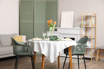 Dining table with setting for International Women's Day celebration and flowers in living room