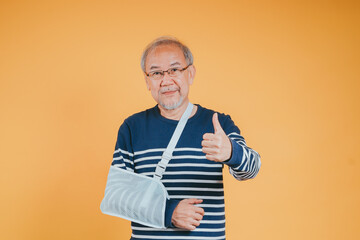 Arm broken. Senior male sling support hand confident smile broken after accident wear arm splint for treatment show good sign. health insurance on mobile concept.