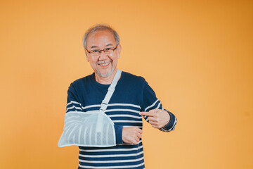 Arm broken. Senior male sling support hand confident smile broken after accident wear arm splint for treatment show good sign. health insurance on mobile concept.