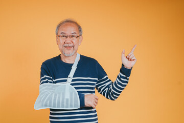Arm broken. Senior male sling support hand confident smile broken after accident wear arm splint for treatment show good sign. health insurance on mobile concept.