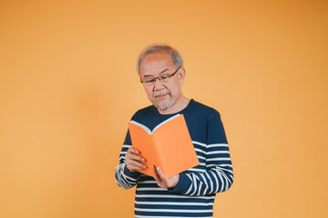 Happy positive senior male smiling and read book education knowledge learning on color background.