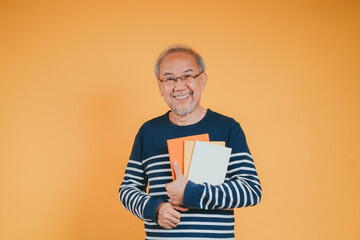 Happy positive senior male smiling and read book education knowledge learning on color background.