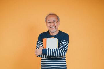 Happy positive senior male smiling and read book education knowledge learning on color background.