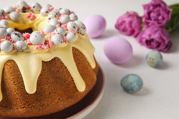 Fototapeta na wymiar Tasty Easter cake, eggs and tulip flowers on light background, closeup