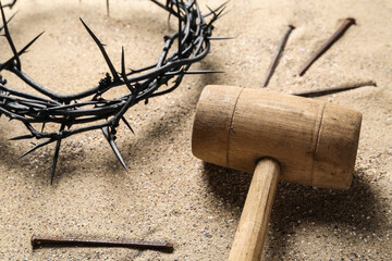 Mallet with crown of thorns and nails on sand, closeup. Good Friday concept