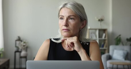 Close up concentrated mature businesswoman work on laptop, looks at computer screen, learns new task, do telework from home, ponders, thinks over question, search solution. Workflow use modern tech