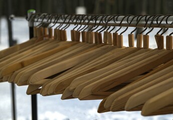 Many wooden hangers on a rod.