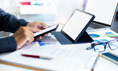 Asian businessman using smart phone to searching stock market data, Successful business people using laptop and tablet computer to analysis investment plan with chart on paperwork, Close-up view