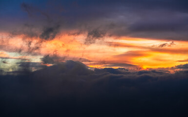 Beautiful sunrise sky. Wallpaper image with amazing coloured orange and dark blue layers of clouds. Nature landscape.