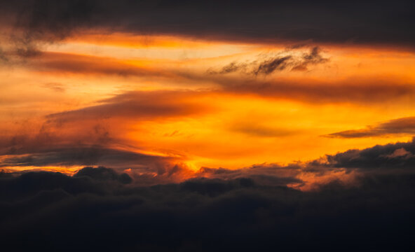Beautiful sunrise sky. Wallpaper image with amazing coloured orange and dark blue layers of clouds. Nature landscape.