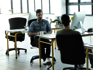 Businessman, startup partnership and friends chat at desk with discussion, advice and conversation at workplace. Entrepreneur group, teamwork and talk in office for idea, planning and company goals