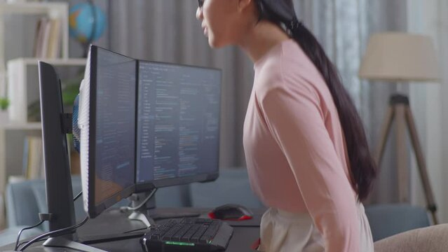 Asian Teen Girl Programmer Walking Into The Working Space Before Sitting To Creating Software Engineer Developing App, Program, Video Game On Desktop Computer At Home
