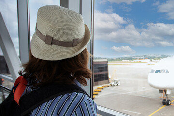 tourist inside the airport looks out the window at the plane before landing, a passenger in the terminal, travel and tourism