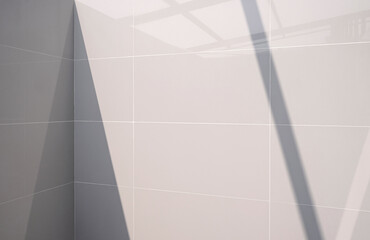Geometric pattern and perspective side view of interior gray tile wall with light reflection and shadow on surface