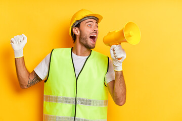 Horizontal shot of distressed handyman holds megaphone screams loudly has angry expression wearing...