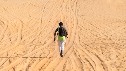 Man seen by back and running on a sand road: sporty man training in the desert, photo - obrazy, fototapety, plakaty