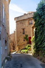 Fototapeta na wymiar A street in Cotignac, a French village in tProvence. It is famous for its troglodyte dwellings that are carved into tufa cliffs covered with large stalactites, and its two feudal towers from 1033.