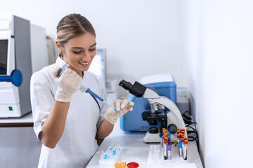 Woman biologist using micro pipette with test tube and beaker for experiment in science laboratory. Biochemistry specialist working with lab equipment and glassware for development.