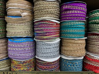 Many rolls of Indian lace fabric with colorful abstract pattern being display in accessories and knitting shop.