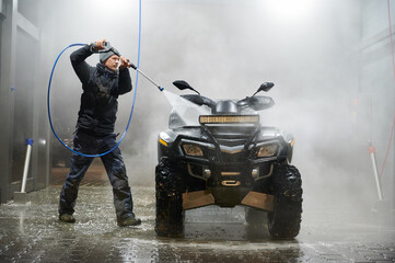 Full length of man washing all-terrain vehicle with high pressure water sprayer auto washer © anatoliy_gleb
