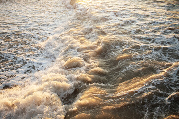 Splashing waves on the pebbly beach On the Sunset