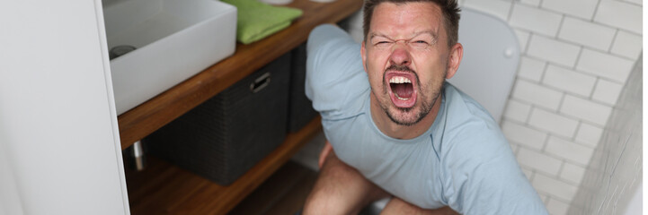 Man suffering from hemorrhoids screams on toilet in toilet