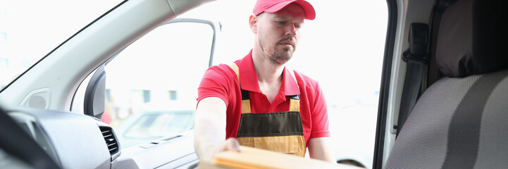 Young delivery man is loading boxes into car