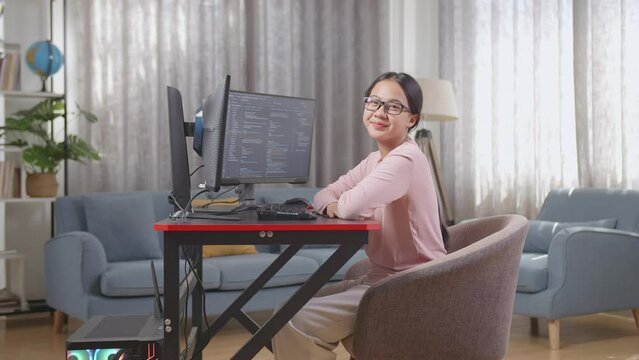 Asian Teen Girl Programmer Smiling To Camera While Creating Software Engineer Developing App, Program, Video Game On Desktop Computer At Home. Terminal With Coding Language 
