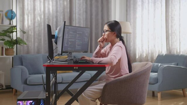 Asian Teen Girl Programmer Yawning While Creating Innovative Software Engineer Developing App, Program, Video Game On Desktop Computer At Home. Terminal With Coding Language 
