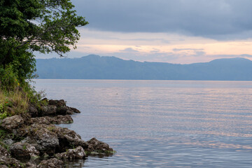 view of the horizon of lake toba in the morning with cloudy weather with a fisherman in the middle of the lake