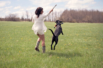 A woman in a white skirt plays with her dog.