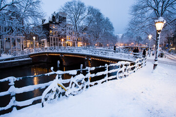 Evening light on the snow covered streets and canals of Amsterdam, the Netherlands.