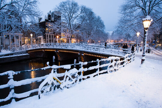 Evening light on the snow covered streets and canals of Amsterdam, the Netherlands. - Powered by Adobe